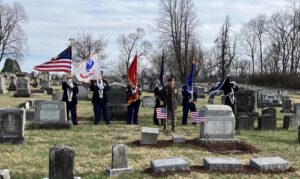 Six men in military uniform in position at gravesite.