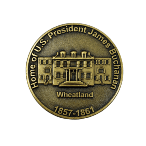 A round, bronze lapel pin with image of Wheatland engraved and text "Home of U.S. President James Buchanan. Wheatland. 1857-1861."